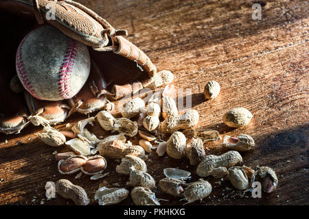 Alte baseball Handschuh und Ball mit Erdnüsse in der Schale auf einem Hintergrund von rustikalen, mit Holz. Nostalgie Konzept oder Thema. Nahaufnahme, Textur Detail Stockfoto