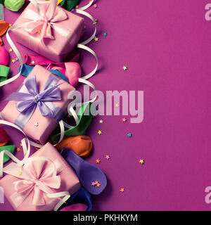 Festliche Hintergrund violett Material bunte Luftballons luftschlangen Konfetti drei Boxen Geschenk. Ansicht von oben flach kopieren Raum toning Stockfoto