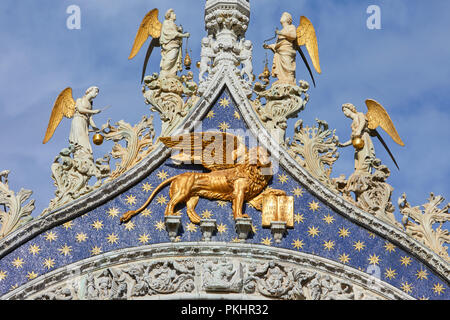 San Marco golden geflügelten Löwen Statue mit Engel auf der Fassade der Basilika, dem Symbol von Venedig an einem sonnigen Tag in Italien Stockfoto