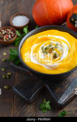 Kürbis Cremesuppe mit Sahne und Kürbiskerne auf rustikalen Holztisch. Stockfoto