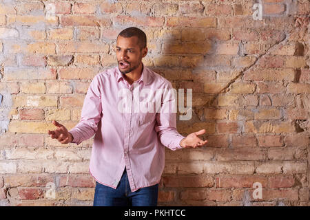 Porträt eines zornigen hübscher junger Mann, der in einem rosa Hemd. Stockfoto