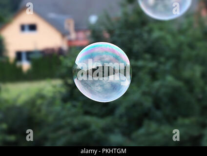 Eine große Blase fliegen in der Luft. Bubble dienen als spiegeln, so dass wir einige Haus und bewölkt sehen können. Blase ist vor allem von Grün und Violett erstellt. Stockfoto