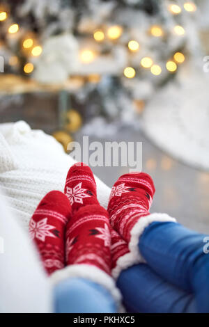 Ein paar Verlegung auf dem Sofa und das Tragen der roten Weihnachten themed Socken. Stockfoto