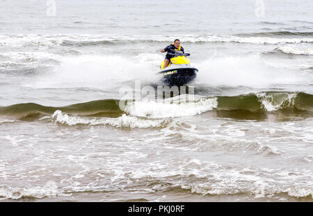 Junger Mann reiten auf Jet Ski, die Tricks auf die Wellen des Meeres im Sommer in der Ostsee, Litauen. Stockfoto