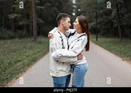 Junges Paar in modischen weißen Pullover umarmen im Park Stockfoto