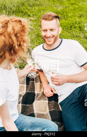 Hohe Betrachtungswinkel von Happy rdhead Paar trinken Wein zum Picknick im Park Stockfoto
