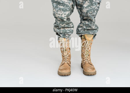 7/8 Schuß von Soldaten in Uniform und Stiefel isoliert auf Grau Stockfoto