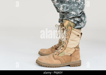 Teilansicht der männlichen Soldaten in der Tarnung Bekleidung und Stiefel auf grauem Hintergrund Stockfoto
