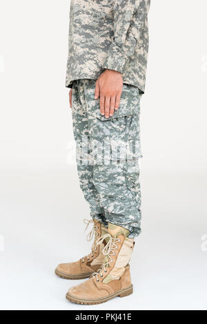Teilansicht der männlichen Soldaten in der Tarnung Bekleidung und Stiefel auf grauem Hintergrund Stockfoto