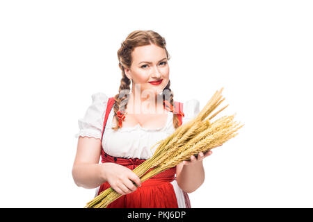 Lächelnd oktoberfest Kellnerin im traditionellen bayerischen Kleid holding Weizenähren isoliert auf weißem Hintergrund Stockfoto