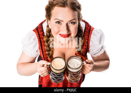 Hohe Betrachtungswinkel und der Oktoberfest Kellnerin im traditionellen bayerischen Kleid holding Becher mit hellen und dunklen Bier auf weißem Hintergrund Stockfoto