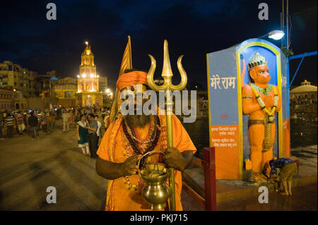 Am Abend Hinduistische devotees Saint sadhu Holding trishul oder Trident in Nashik Kumbha Mela Panchavati in Maharashtra Indien Stockfoto