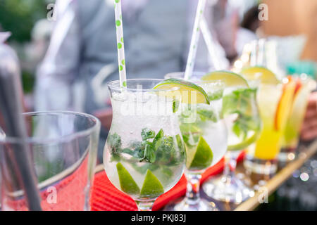 Der Barkeeper macht cocktail Mojito. Glas, selektiven Fokus besprühen. Alkoholische Getränke auf der Grundlage von Theke mit Eiswürfeln und Lyme. Party im Freien Stockfoto