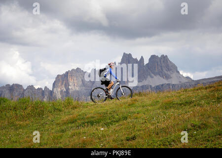 Cortina d'Ampezzo, Italien - 18. August 2018: Ein solo Radfahrer pedal bergauf auf dem Berg weg, an einem bewölkten Sommertag. Im Hintergrund der Gipfel des Stockfoto