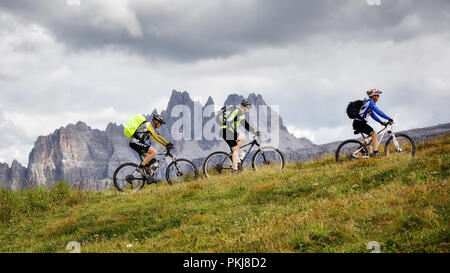 Cortina d'Ampezzo, Italien - 18 August, 2018: Einige Mountainbiker pedal bergauf auf dem Berg weg an einem bewölkten Sommertag. Im Hintergrund der Gipfel Stockfoto