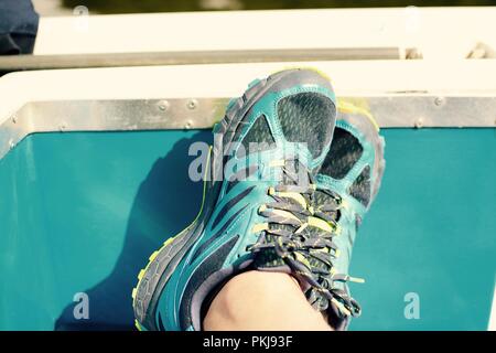 Entspannen mit Füßen auf einem Boot, männlich in Ausbildung Schuhe, Filter angewendet Stockfoto