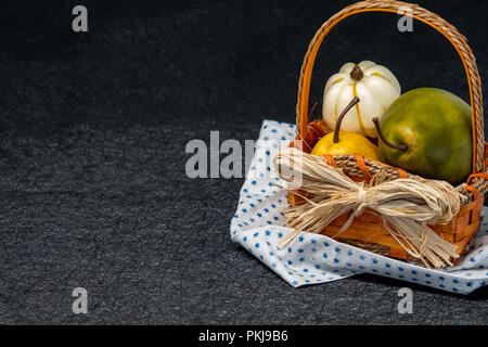 Birnen in einem Strohkorb. Serviette mit Sternenmuster. Schwarzer Hintergrund, isoliert. Konzept für Herbst und im Herbst Stockfoto