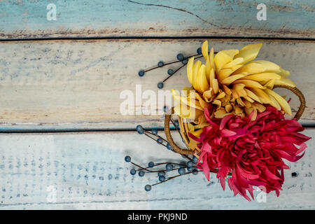 Schönen Herbst Blumenarrangement mit gelb und rosa Mamas in einem Strohkorb. Blau Holz- Hintergrund Stockfoto