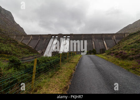 Straße nach Ben Crom Stausee im Herzen der Mourne Mountains. Wasser ist eine Kaskadierung auf dem Damm. Stockfoto