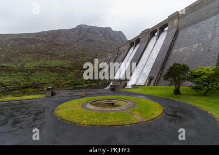 Wasser ist eine Kaskadierung der Staumauer am Ben Crom Behälter. Im Herzen der Mourne Mountains. Ben Crom Berg oberhalb der Staumauer gesehen. Ein Ci Stockfoto