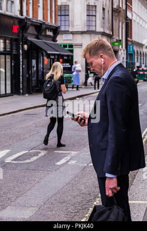 Menschen mit mobilen Geräten auf der Street, Westminster, London, England, Großbritannien Stockfoto