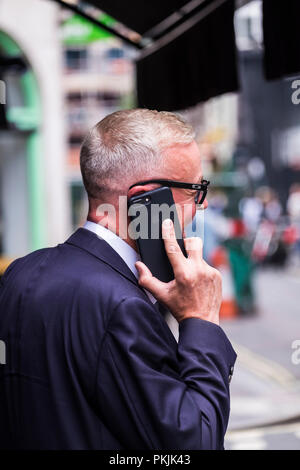 Menschen mit mobilen Geräten auf der Street, Westminster, London, England, Großbritannien Stockfoto