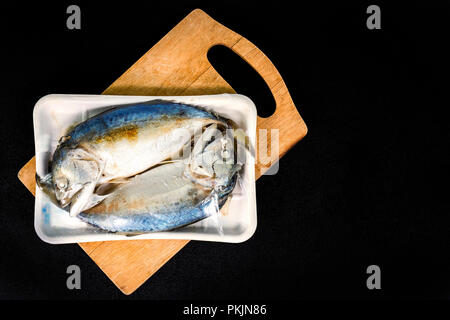 Zwei Fische in Verpackungen aus Supermarkt auf der Holzplatte. Stockfoto