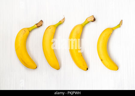 Vier frische Bananen auf Holztisch. Blick von oben. Stockfoto