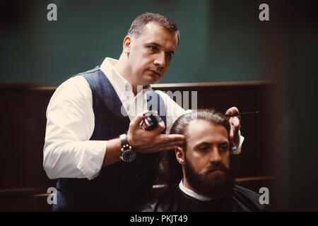 Barbershop mit Interieur aus Holz. Bärtige Modell Mann und Friseur. Stockfoto