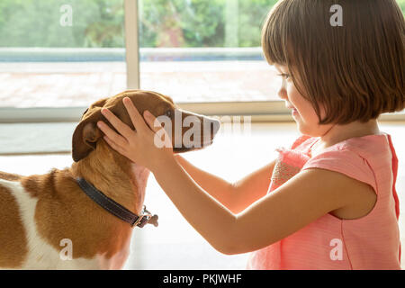 Ein Kleinkind Mädchen den Kopf Ihres Welpen halten in ihren Händen Stockfoto