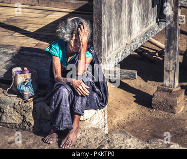 Ältere Frau von der 1200 Jahre alten Bena Dorf in der Nähe von bajawa Stadt, auf der Insel Flores, Schilde ihr Gesicht von der beißenden Sonne. Stockfoto