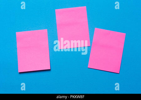 Drei Leere rosa Notizen, einen Aufkleber auf dem blauen Hintergrund für das Schreiben von Ideen und Aufgaben Stockfoto