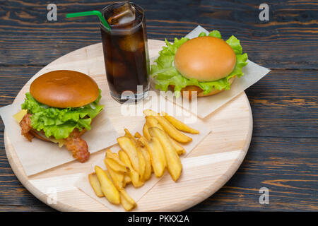 Doppelzimmer mit käse und bacon Burger mit Limo und Pommes frites auf einem runden Holzbrett serviert auf einem rustikalen Tisch oder Theke Stockfoto