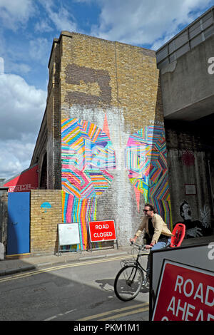 Mann auf dem Fahrrad radfahren Vergangenheit Graffiti an der Wand von Gebäude in New Inn Hof, Shoreditch East London UK KATHY DEWITT Stockfoto