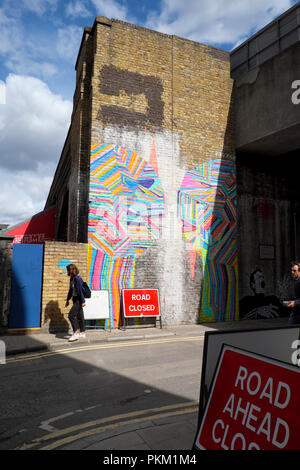 Junge Frau Vergangenheit Graffiti gehen auf Wand von Gebäude in New Inn Hof, Shoreditch East London UK KATHY DEWITT Stockfoto