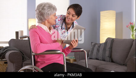 Asiatische Frau und älteren Patienten sprechen mit Tablet Stockfoto
