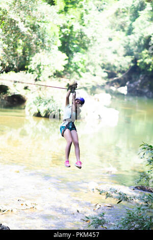 Happy girl in-motion auf Zipline im tropischen Dschungel Regenwald Baumkronen Stockfoto