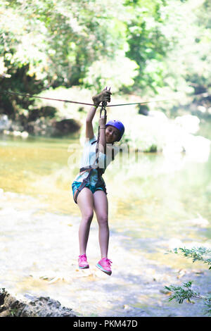 Happy girl in-motion auf Zipline im tropischen Dschungel Regenwald Baumkronen Stockfoto