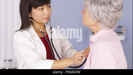 Asiatische Arzt hören auf das Herz des älteren Patienten Stockfoto