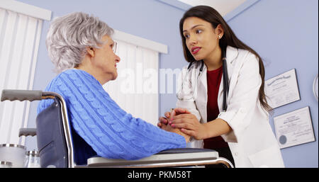 Hispanic Frau Doktor tröstlich für behinderte ältere Patienten Stockfoto