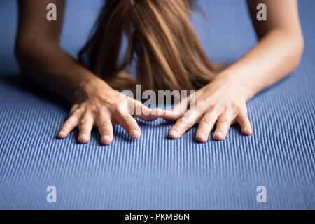 Sportliche frau yoga auf eine blaue Matte Stockfoto