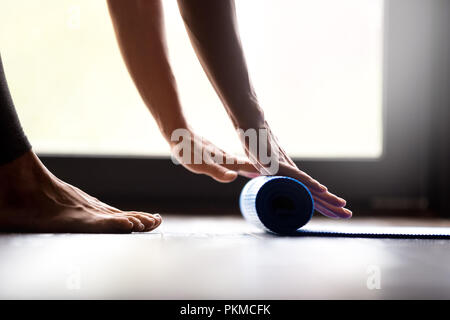 Junge Frau rolling Fitness Matte, Hände, Nahaufnahme Stockfoto