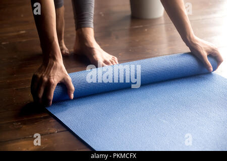 Zeit für die Praxis, weibliche Hände abrollen blau Yogamatte Stockfoto