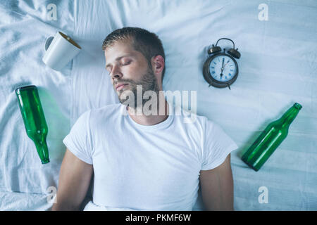 Jungen gutaussehenden Mann im Bett am Morgen nach der Nacht Trinken Stockfoto