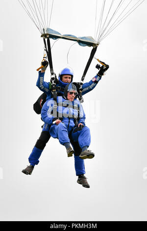 D-Day Veteran Las Harry, 94, steigt unter seinem Fallschirm zu Chief Instructor Ryan Mancey an Old Sarum Flugplatz, Salisbury, Wiltshire, wo er ist, die an seiner ersten Hohe skydive, seit er in der Normandie am 6. Juni 1944 mit dem Fallschirm verbunden. Stockfoto