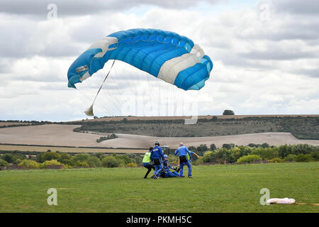 D-Day Veteran Las Harry, 94, landet sicher unter seinem Fallschirm zu Chief Instructor Ryan Mancey an Old Sarum Flugplatz, Salisbury, Wiltshire, wo er ist, die an seiner ersten Hohe skydive, seit er in der Normandie am 6. Juni 1944 mit dem Fallschirm verbunden. Stockfoto