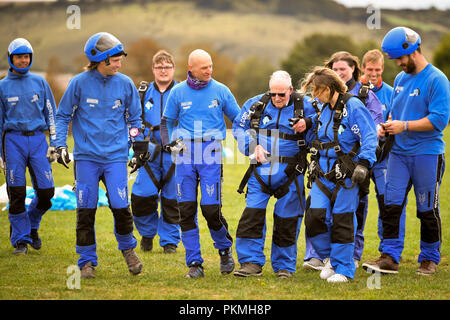 D-Day Veteran Las Harry, 94, ist geholfen zurück von der Landezone zu gehen nach einer sicheren Landung Old Sarum Flugplatz, Salisbury, Wiltshire, wo er ist, die an seiner ersten Hohe skydive, seit er in der Normandie am 6. Juni 1944 mit dem Fallschirm. Stockfoto