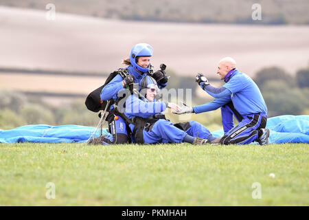 D-Day Veteran Las Harry, 94, ist zu beglückwünschen, wie er landet sicher unter seinem Fallschirm zu Chief Instructor Ryan Mancey an Old Sarum Flugplatz, Salisbury, Wiltshire, wo er ist, die an seiner ersten Hohe skydive, seit er in der Normandie am 6. Juni 1944 mit dem Fallschirm verbunden. Stockfoto