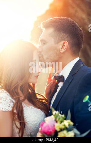 Schönes Paar in der Liebe das Küssen in Nahaufnahme. Hochzeit paar Küssen bei Sonnenuntergang und Wellen der Liebe und zärtliche Gefühle. Verliebtes Paar im Urlaub. Wed Stockfoto