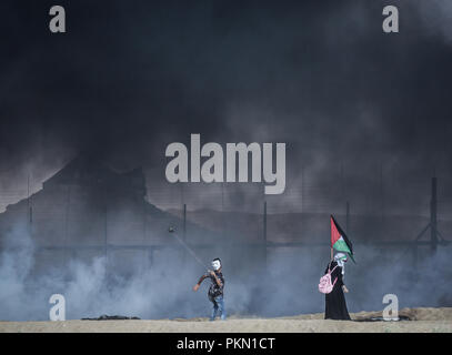 Gaza, Gaza, Gaza. 14 Sep, 2018. Ein palästinensischer Mann mit einer Schleuder Steine gegen israelische Truppen während der Auseinandersetzungen zu werfen. Auseinandersetzungen zwischen palästinensischen Demonstranten und israelischen Kräfte während eines Protestes entlang der israelischen Zaun östlich von Gaza-stadt. Credit: nidal Alwaheidi/SOPA Images/ZUMA Draht/Alamy leben Nachrichten Stockfoto